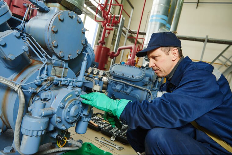 Refrigeration technician servicing an industrial compressor